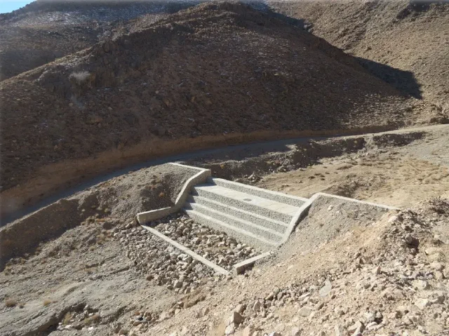 مانع بتنی پلکانی در بستر خشک و سنگی رودخانه در پای تپه